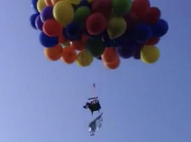 Il vole avec une chaise de jardin et des ballons d'hélium