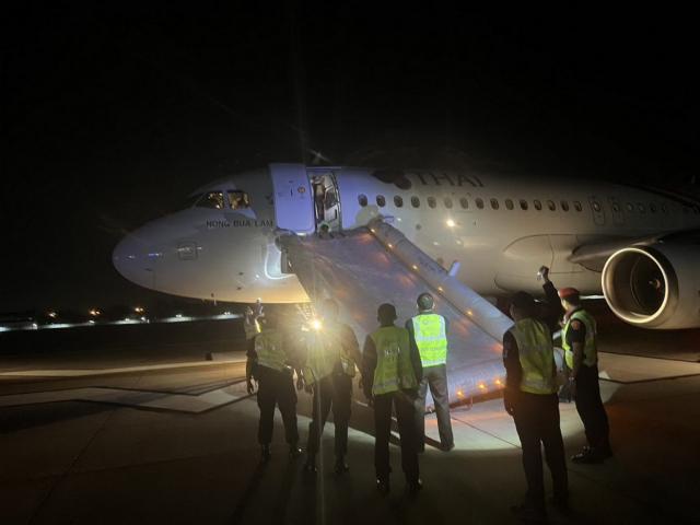 Un passager ouvre un toboggan d'un avion de Thai Airways